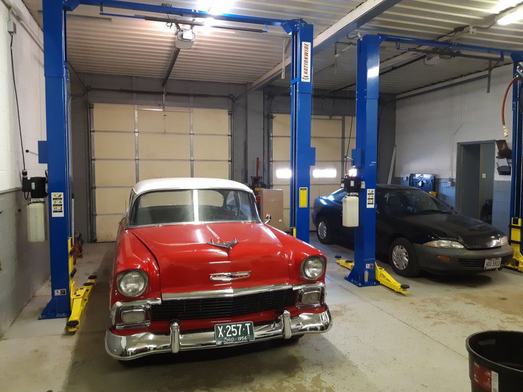 Classic red car on a lift inside the Last Stop Auto Shop garage